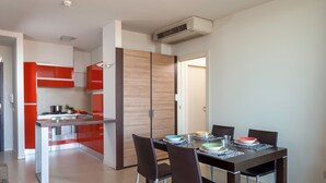Una cocina moderna con armarios rojos, una mesa de comedor con sillas y una estufa a la vista.