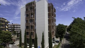 Un edificio moderno de varios pisos con un patio central, balcones y un área de estacionamiento.