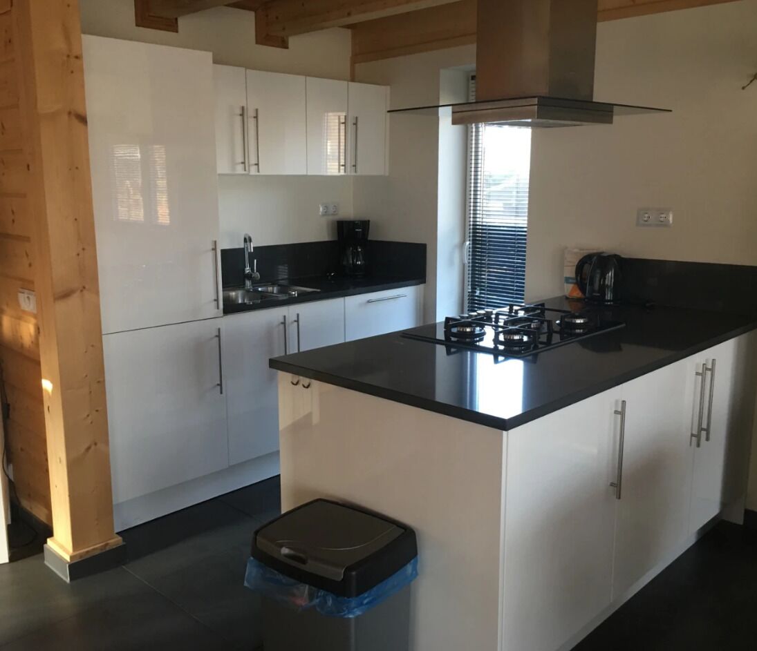 Een moderne keuken met witte kastjes, een zwart aanrecht en een gasfornuis.