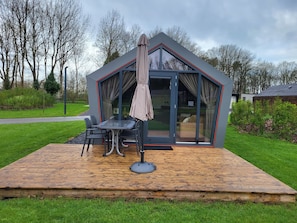 Una casa moderna y compacta con puerta de vidrio y un patio con mesa y sillas.