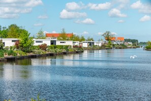 A waterfront property with modern buildings, a calm water body, and a swan in the distance. - EuroParcs Veluwemeer (Nunspeet)