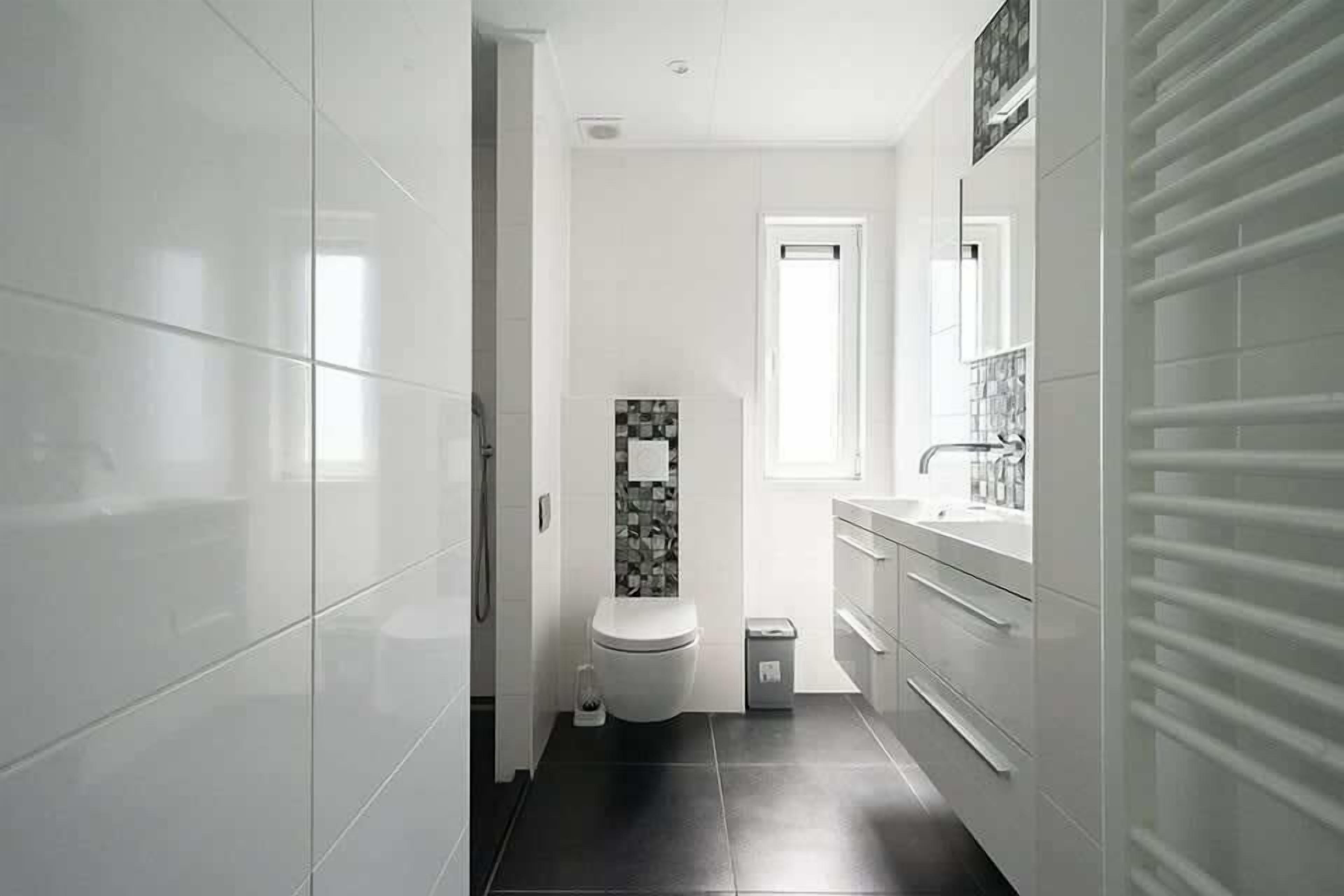 A modern bathroom with a toilet, sink, and mirror.