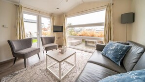 A modern living room with a sofa, armchairs, a coffee table, and a TV. - EuroParcs Veluwemeer (Nunspeet)