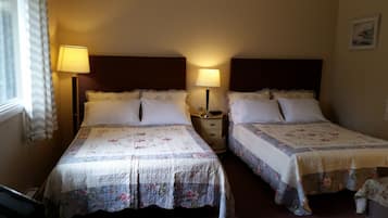 Dos camas individuales con ropa de cama floral, mesitas de noche con lámparas y una ventana con cortinas.