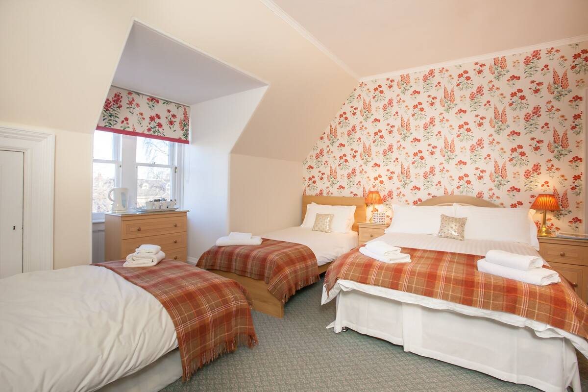 A bedroom with two beds, a dresser, and a window.