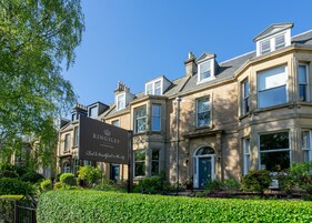 Un histórico hotel Kingsley en Edimburgo con fachada de piedra tradicional, grandes ventanales y un jardín bien cuidado.