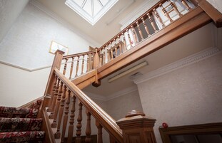 Una imponente escalera con barandales de madera y un elegante suelo estampado.