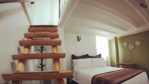 A bedroom with a wooden ladder, a bed with white bedding, and a green wall with decorative plates. - Kori Gems Inn (Cusco)