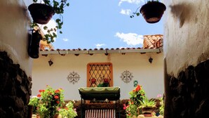 A courtyard with a bench, hanging plants, and a tiled floor. - Kori Gems Inn (Cusco)