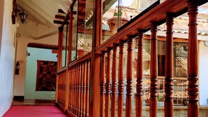 A corridor with wooden balusters and a red carpet, leading to a room with a view of the outside. - Kori Gems Inn (Cusco)
