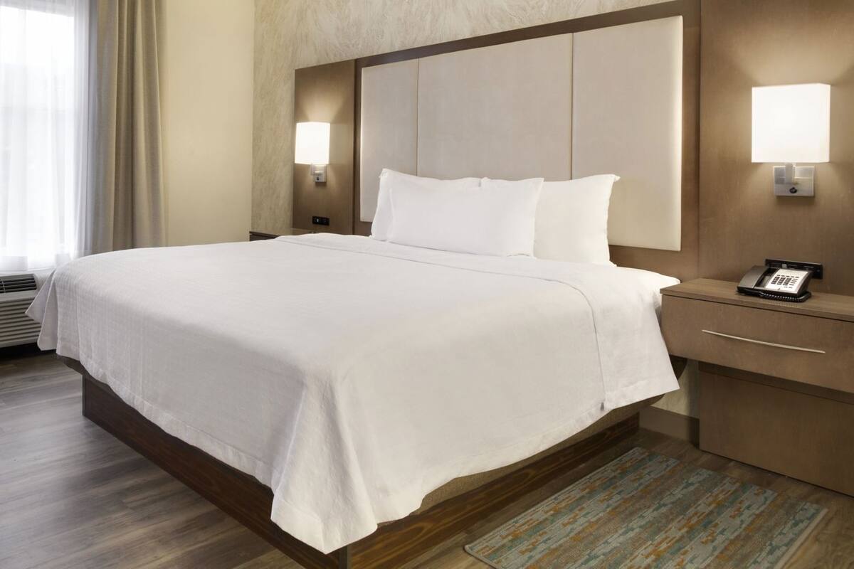 A hotel room with a large bed, bedside lamps, a telephone, and a ceiling fan.