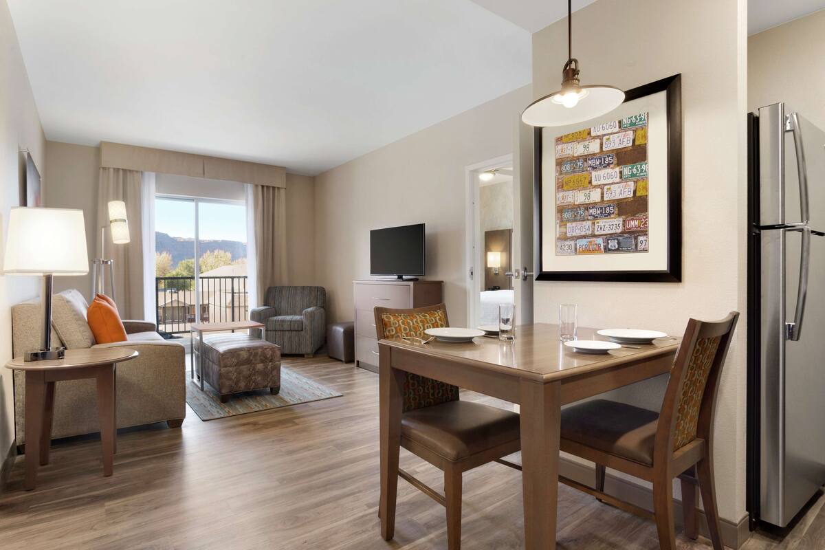 A hotel room with a dining area, a television, and a refrigerator.