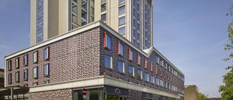 Un bâtiment moderne avec une façade en briques, de nombreuses fenêtres et un ciel dégagé.