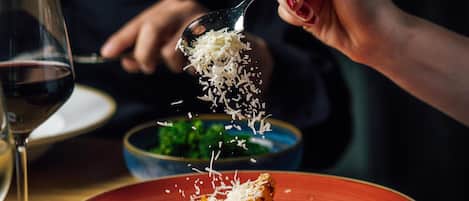 A person serving pasta with grated cheese.