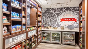 Una sección de snacks y bebidas bien organizada, con estantes llenos de diversas opciones y un letrero que dice 'Delicias' sobre una exhibición variada.