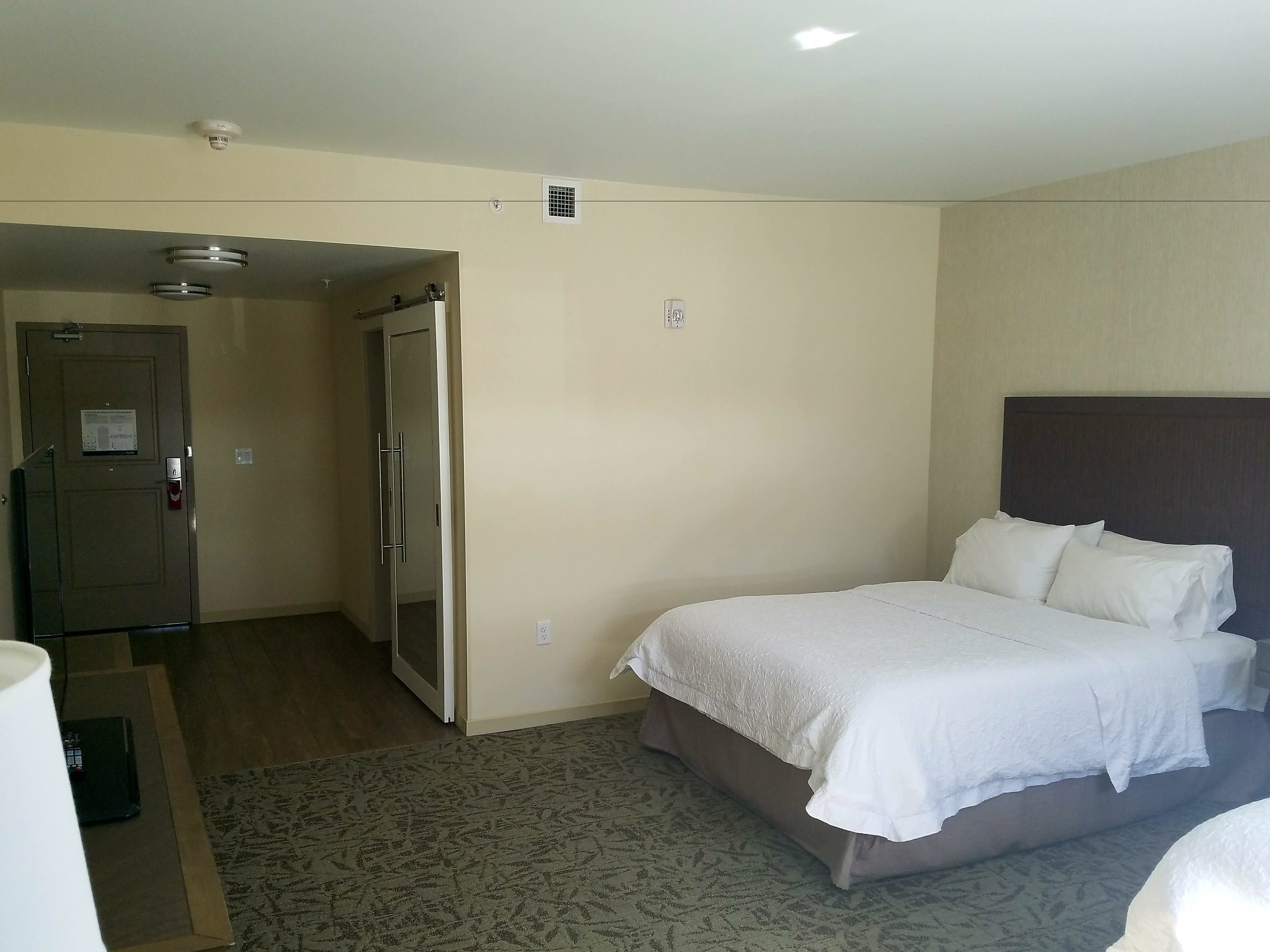 Una habitación de hotel con una cama, un escritorio y una puerta que da a otra habitación.
