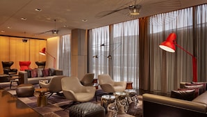 A modern living room with leather sofas, a coffee table, and a red floor lamp. - Park Plaza London Park Royal (London)