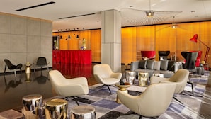 A modern lobby with leather sofas, a reception desk, and a unique ceiling light fixture. - Park Plaza London Park Royal (London)