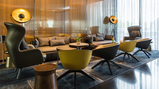 A modern lounge area with a sofa, yellow chairs, and a floor lamp. - Park Plaza London Park Royal (London)