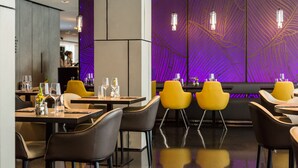 A modern restaurant interior with tables, chairs, and purple wall decor. - Park Plaza London Park Royal (London)