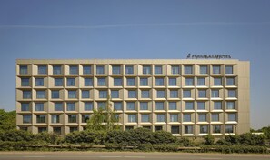 Ein modernes Hotelgebäude mit symmetrischer Fassade, zahlreichen Fenstern und einem Schild mit der Aufschrift 'Park Plaza Hotel'.