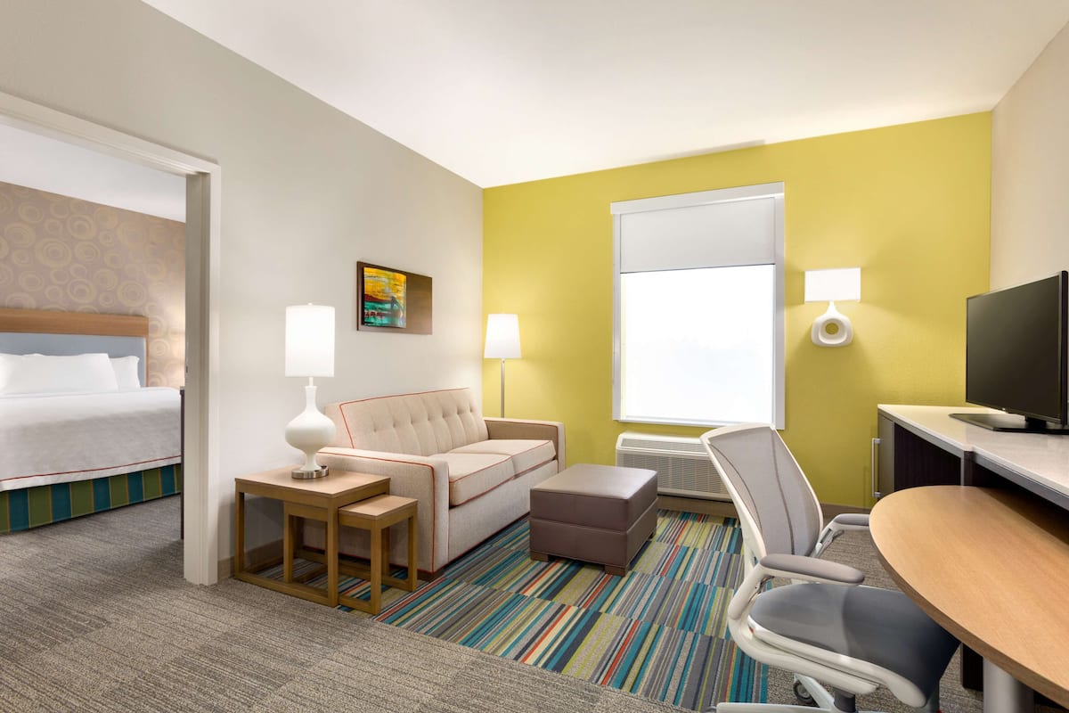 Een hotelkamer met een bed, bank, fauteuil, klein tafeltje en een televisie.