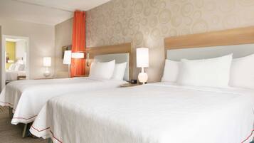 A hotel room with two beds, each with a headboard, bedside lamps, and a mirror.