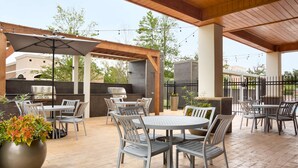 Une terrasse extérieure avec des tables et des chaises, un barbecue et des guirlandes lumineuses.