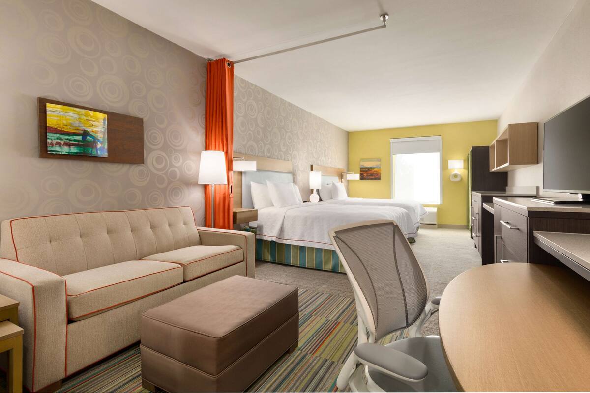 Een hotelkamer met een bed, een slaapbank, een stoel, een bureau en een televisie.