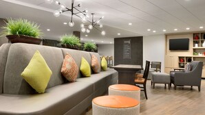 Un salon moderne avec un canapé, des poufs, une table basse et un téléviseur.