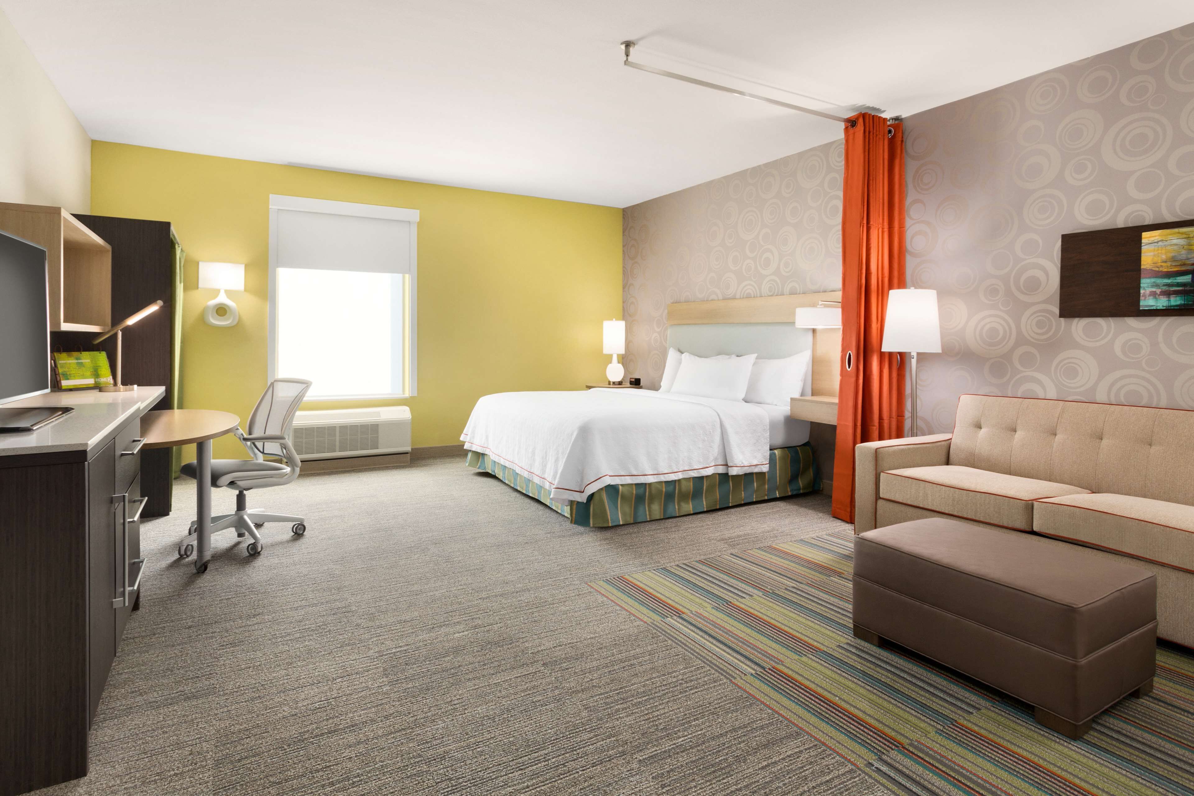 A hotel room with a bed, a sofa, a desk, and a chair.
