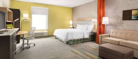 A hotel room with a bed, a sofa, a desk, and a chair.