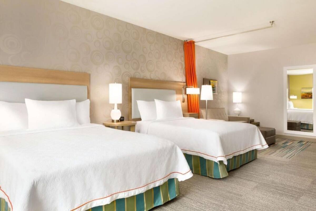 Een hotelkamer met twee bedden, een groot raam en uitzicht op de stad.