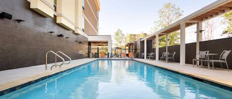 A swimming pool with a covered seating area and a building with a modern design.