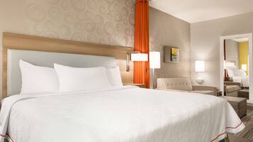 A hotel room with a large bed, a headboard, a nightstand with a lamp, a chair, and a mirror.