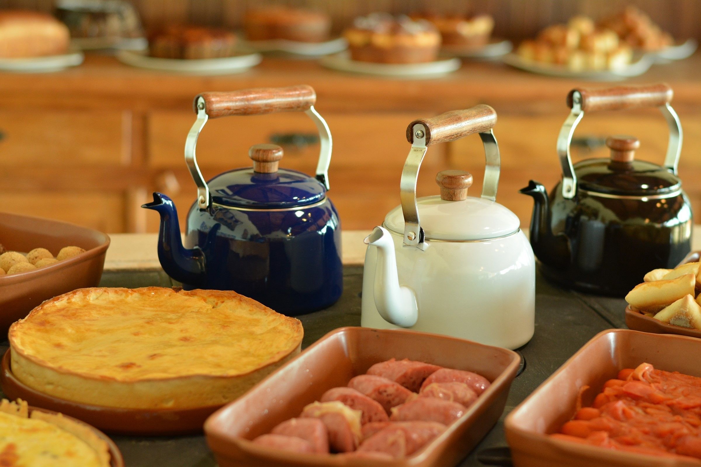 A buffet table with various food items and two kettles.