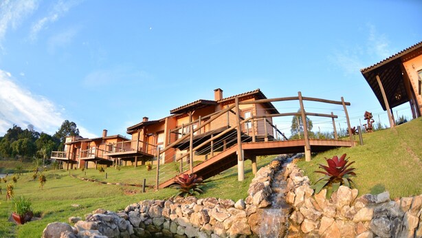 A modern resort with multiple buildings, a stone water feature, and a well-maintained lawn. - Pousada Villa dos Leais (Serra Negra)