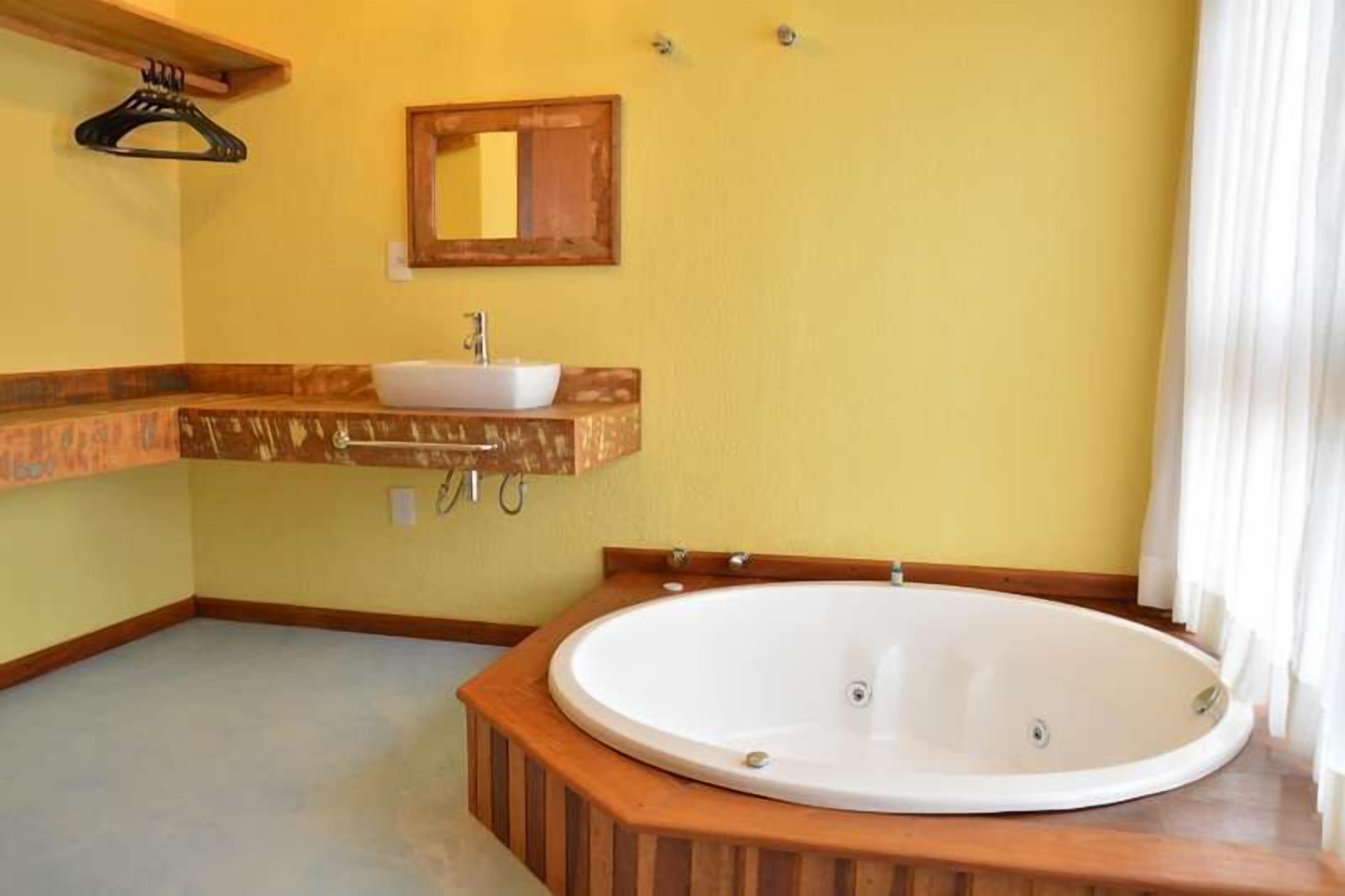 Un baño con tocador de madera, un lavamanos blanco y una bañera independiente.