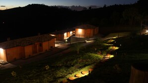 A nighttime view of a building with a tiled roof and a well-lit entrance. - Pousada Villa dos Leais (Serra Negra)