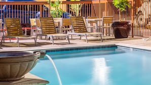 A pool area with lounge chairs and a hot tub.