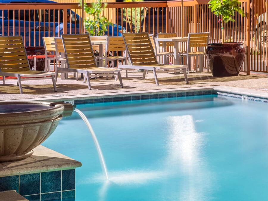 A pool area with lounge chairs and a hot tub.