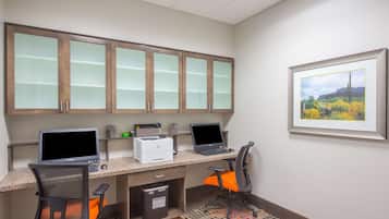 A workspace with two desks, computers, chairs, and cabinets.