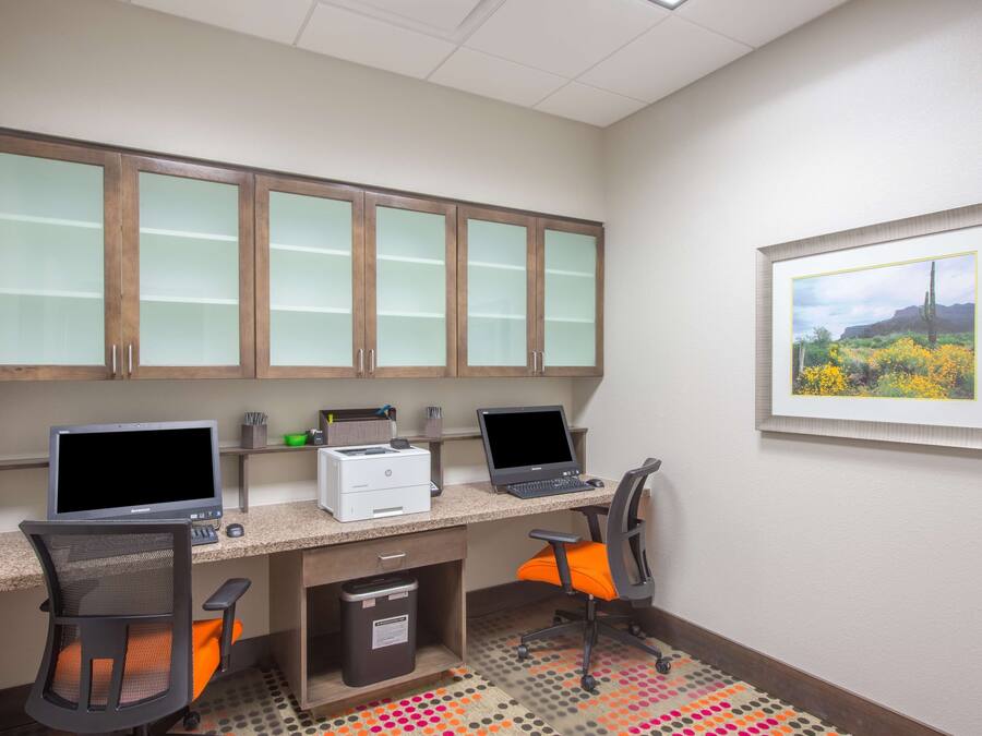 A workspace with two desks, computers, chairs, and cabinets.