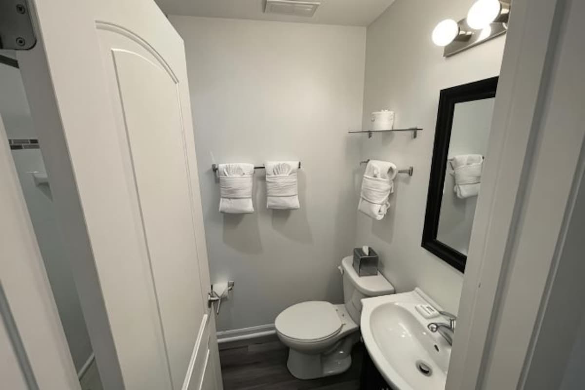A bathroom with a toilet, sink, and mirror.
