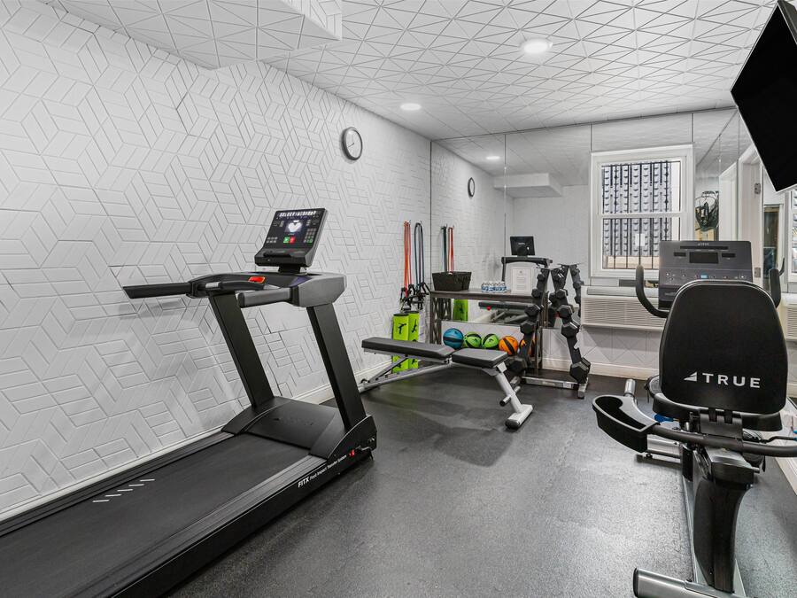 A gym with a treadmill, weight bench, and exercise equipment.