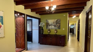Un pasillo con techo de madera, suelo de baldosas, un armario con lámparas decorativas y un cuadro en la pared.