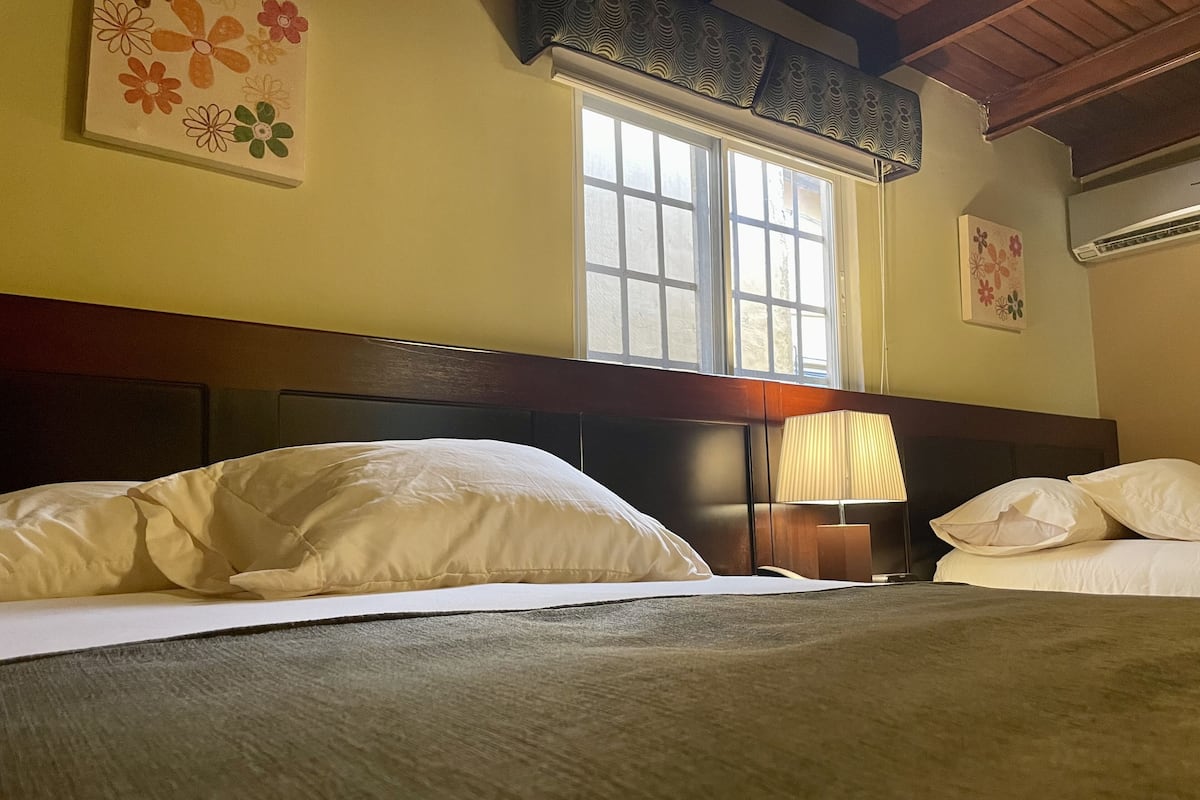 Une chambre d’hôtel avec un grand lit, une fenêtre donnant sur un beau paysage et un mur décoré d’œuvres d’art florales.
