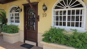 Una casa con una puerta marrón, dos ventanas arqueadas y el número 19 en la pared.