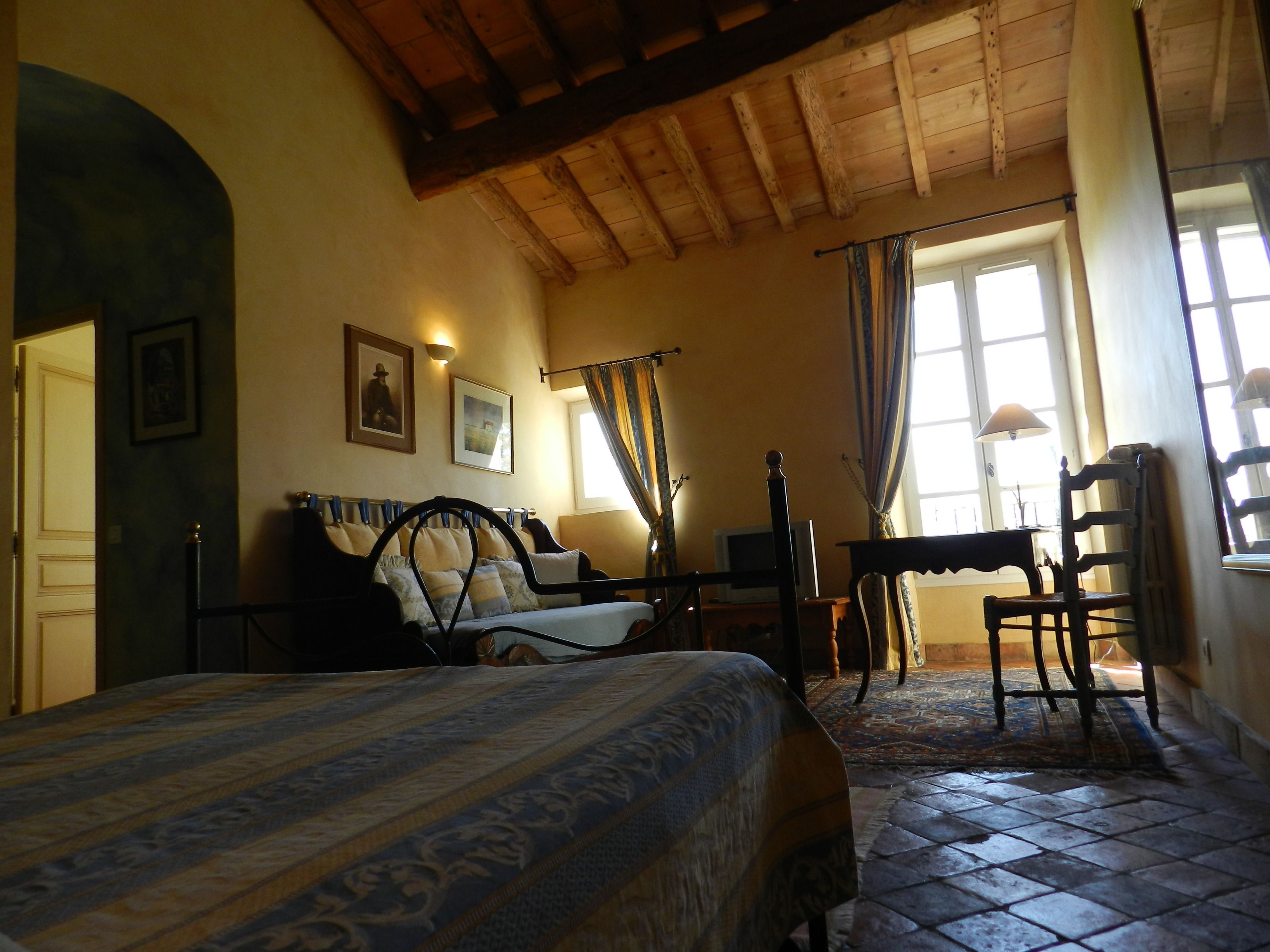 A bedroom with a bed, a desk, a chair, and a television.