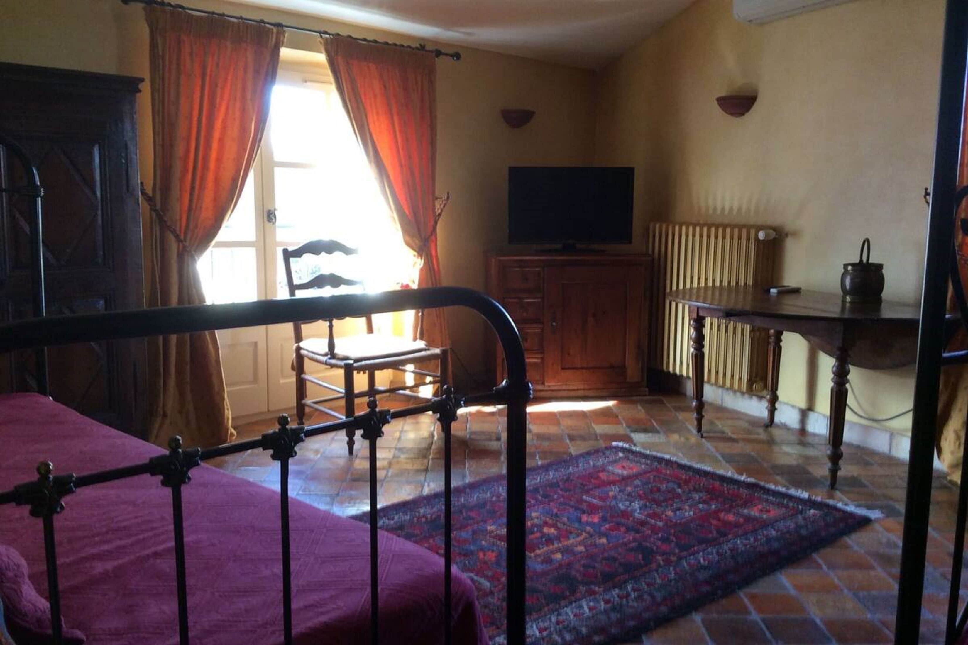 Un dormitorio con cama, un armario de madera, televisor y radiador.